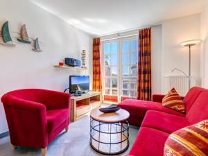 a living room with two red chairs and a tv at Residenz am Balmer See - BS 48 mit Wellnessbereich in Balm +12 photos