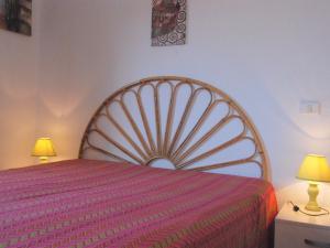 a bedroom with a bed with a pink bedspread and two lamps at Apartment Il Seccione-1 by Interhome in Portoferraio