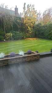 a wooden deck with three plants in a garden at Lavish4Bed Mansion in Warrington in Warrington