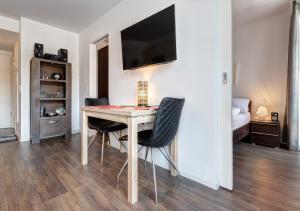 a dining room table with two chairs and a television on a wall at Residenz am Balmer See - BS 56 mit Wellnessbereich in Balm