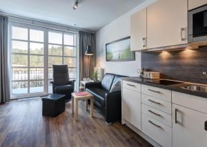 a kitchen and living room with a couch and a chair at Residenz am Balmer See - BS 56 mit Wellnessbereich in Balm +14 photos