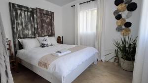 a bedroom with a bed with white sheets and a window at Tranquil flatlet with Full Kitchen & Pool Access in Johannesburg +5 photos