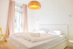 a white bedroom with a large bed with a window at Ferienhaus Loddinperle mit Sauna in Loddin