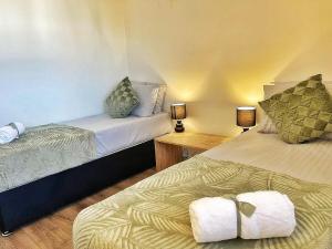 two beds in a room with two lamps and towels at Modern 3 Bed House In Essex By DLuxoria Short Lets & Serviced Accommodation With Pet Friendly, Free WiFi & Free Parking in Basildon