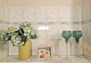 a yellow vase with flowers and a picture and two wine glasses at Bella Vita in Trassenheide +10 photos