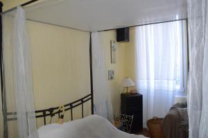 1 dormitorio con cama con dosel y ventana en Volets Bleus et Briques Rouges, en Albi
