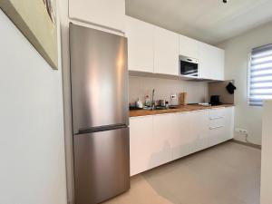 a stainless steel refrigerator in a kitchen with white cabinets at Villa Majunaxa in Corralejo