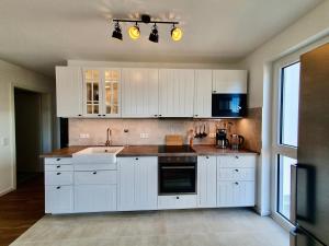 a kitchen with white cabinets and a sink at Bernsteinquartier BQ1182 - Ankerplatz in Kolpinsee