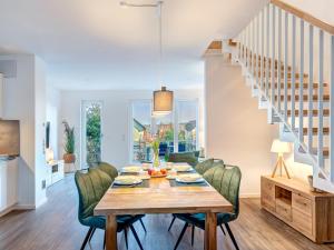 een eetkamer met een houten tafel en groene stoelen bij Bersteinquartier BQ 10c in Kolpinsee