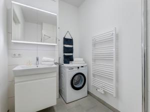 eine weiße Waschküche mit Waschmaschine und Waschbecken in der Unterkunft Bernsteinquartier BQ 0558 - Eichenkrone in Ostseebad Kölpinsee