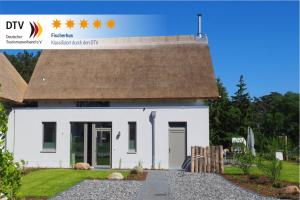 a small white house with a brown roof at Fischerhus Loddin mit Sauna und Kamin in Loddin