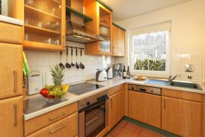 a kitchen with wooden cabinets and a bowl of fruit on the counter at Ferienhaus am Eikboom - DHH1 mit Fasssauna in Ostseebad Karlshagen +4 photos