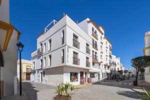 un grand bâtiment blanc dans une rue de la ville dans l'établissement BHost - Puro Tarifa, à Tarifa