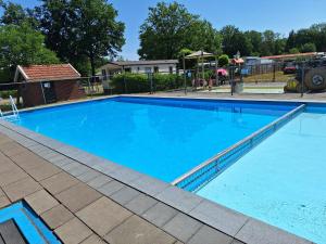 a large swimming pool with blue water at Stacaravan Diepenheim in Diepenheim