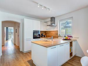 Villa Strandperle Wohnung 28/29 Bansin في بانسين: مطبخ بخزائن بيضاء وطاولة خشبية +18 صورة