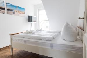 une chambre blanche avec un lit avec une télévision dessus dans l'établissement Meerferienhaus - Haus Schlehenweg, à Zinnowitz