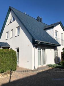 une maison blanche avec un toit noir dans l'établissement Meerferienhaus - Haus Schlehenweg, à Zinnowitz
