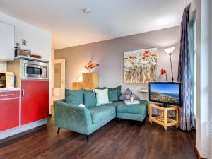 ein Wohnzimmer mit einem blauen Sofa und einem Fernseher in der Unterkunft Villa Margot - FeWo 02 in Bansin