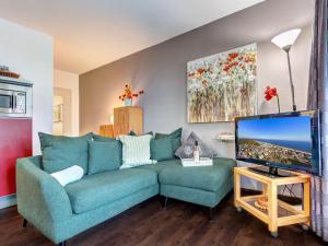 ein Wohnzimmer mit einem blauen Sofa und einem Fernseher in der Unterkunft Villa Margot - FeWo 02 in Bansin