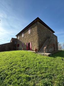un vecchio edificio in mattoni con porte rosse su un campo verde di IL MELOGRANO a Scarlino Altre 8 foto
