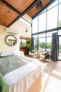 a bedroom with a large bed and large windows at Charming Tiny House with Small Pool & Fire Pit in Lagartero +18 photos