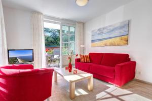 a living room with two red couches and a table at Residenz am Balmer See - BS 45 mit Wellnessbereich in Balm