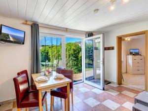 comedor con mesa, sillas y puertas correderas de cristal en Bungalow Konrad, en Trassenheide