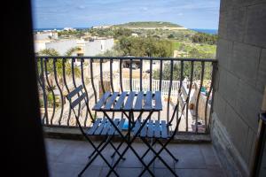 a table and chairs on a balcony with a view of the ocean at Il figolla farmhouse in Xagħra