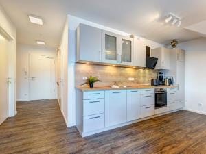 a kitchen with white cabinets and a wooden floor at Bernsteinquartier BQ 0446 in Kolpinsee +9 photos