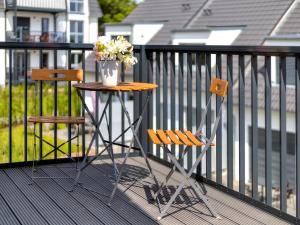 two chairs and a table with flowers on a balcony at Bernsteinquartier BQ 0446 in Kolpinsee