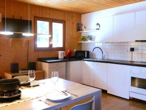 a kitchen with white cabinets and a table with wine glasses at Apartment Prou Riverside by Interhome in Campo Blenio