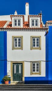 a blue and white house with a green door at Casa das Escadinhas in Ericeira