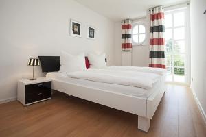 a white bedroom with a large bed and a window at Residenz am Balmer See - BS 01 mit Wellnessbereich in Balm