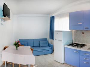 een kleine keuken met een blauwe bank en een tafel bij Holiday Home Villaggio San Pablo-4 by Interhome in Vieste