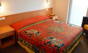 Habitación de hotel con cama con manta roja en Garni Cremona, en Bresanona