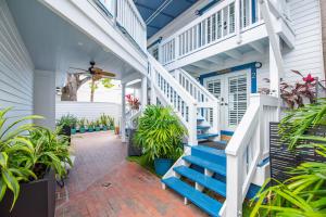 uma varanda com escadas azuis e plantas em Chicken Run at Custom House Inn em Key West