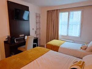 a hotel room with two beds and a television at The Originals Boutique, Hôtel d'Angleterre, Le Havre, centre, plage in Le Havre