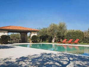 a swimming pool with red chairs and a gazebo at CasaVivi Isolati in Puglia in Putignano