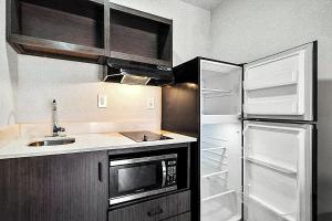 a small kitchen with a refrigerator and a sink at Southern Suites Douglasville in Douglasville +2 photos