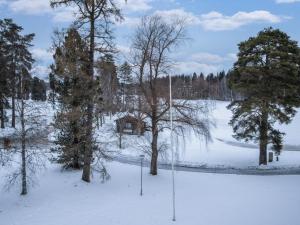 ein schneebedecktes Feld mit Bäumen und einem Haus in der Unterkunft Holiday Home Kylpylä-hotelli- room 442 by Interhome in Ikaalinen