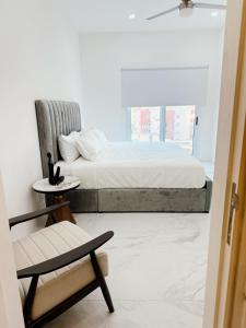 a bedroom with a bed and a chair and a window at Apartamento 3 Recamaras en MAREA Los Cabos Playa Médano CSL in Cabo San Lucas