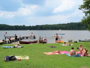 a group of people laying on the grass at a lake at Apartment Müritz Ferienpark Röbel-55 by Interhome in Röbel +9 photos