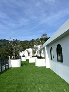 a yard with white walls and green grass at Fantasea Condo Kamala in Kamala Beach