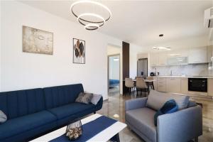 a living room with a blue couch and a kitchen at Aladia Apartment Nikiti in Nikiti