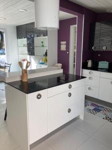 eine Küche mit weißen Schränken und einer schwarzen Arbeitsplatte in der Unterkunft Pitchounette villa Canaulaise 3ch 8p in Lacanau + 33 Fotos