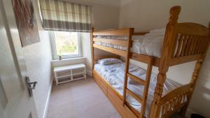 two bunk beds in a room with a window at 3 bedroom home by the beach in Broad Haven