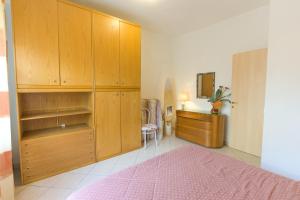 una camera con armadi in legno e letto rosa di Appartamenti Vacanze Roberta a San Vincenzo