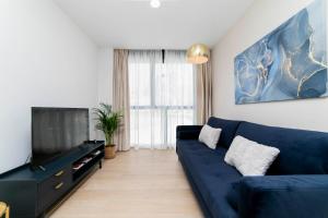 a living room with a blue couch and a tv at Aurora Stays by Charming - Parking cubierto gratis in Madrid