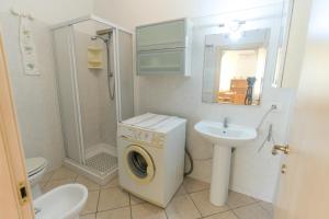 un bagno con lavatrice e lavandino di Appartamenti Vacanze Roberta a San Vincenzo Altre 10 foto