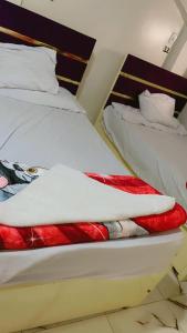 a bedroom with two beds with white and red sheets at waleed home in Jazīrat Aswān